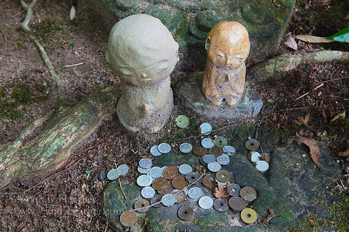 Jizo sama statuettes next to pile of Japanese coins