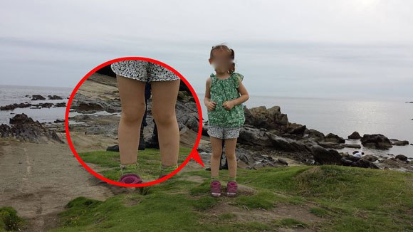 Foreign tourist in Japan snaps a photo of the sea, his daughter, and maybe a ghost