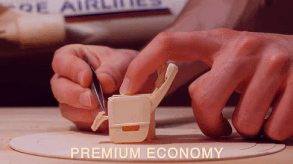 Artist takes paper planes to the next level, builds tiny seats complete with tray tables【Video】
