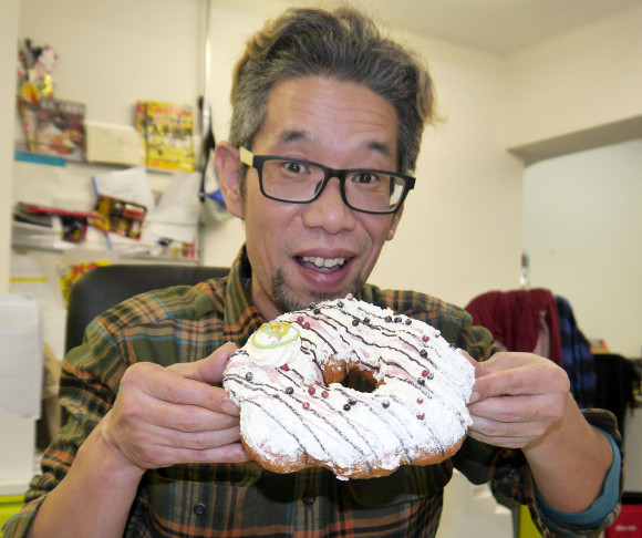 Mr Sato gets his mouth around the new “Big Doughnut” from Mister Donut