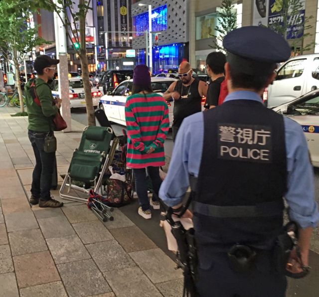 The cops kick Mr. Sato off the street during his attempt to wait on sidewalk for the new iPhone